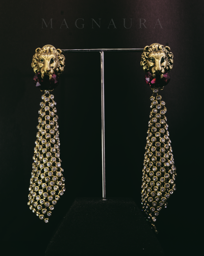 Real studio photograph of the MAGNAURA Gilded Lion drop earrings on a dark display stand