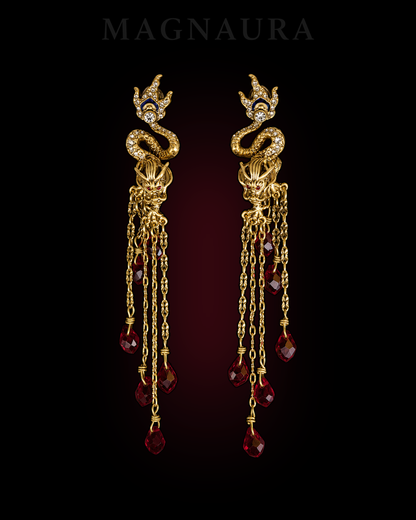 Pair of MAGNAURA Crowned Dragon drop earrings against a deep crimson chamber